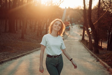 Young woman smiling in the sunshine, thinking about the February 2022 monthly horoscope for her zodi...