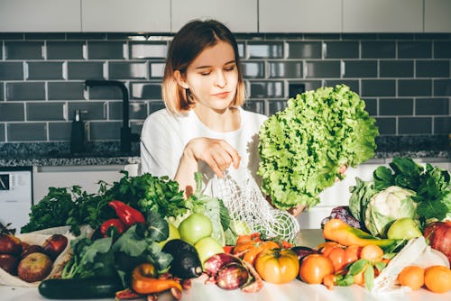 A woman fixes a salad in a modern kitchen. Here's your daily horoscope for January 21, 2022.