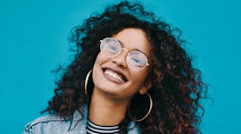 Young woman smiling while standing against a blue wall,  thinking about the fact that February 2022 ...