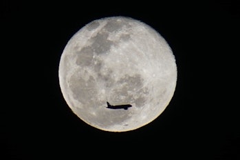 SAN SALVADOR, EL SALVADOR - JANUARY 18: An airplane flights by the moon as it rises in San Salvador,...