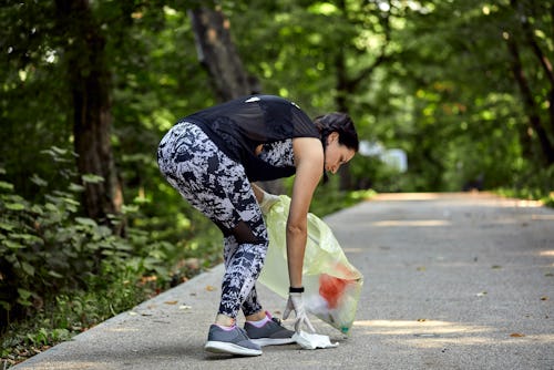 A woman picks up litter while jogging. The plogging trend on TikTok, explained.