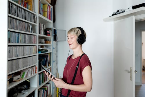 A woman wearing wired headphones examines a CD collection. An astrologer explains Aquarius Zodiac si...
