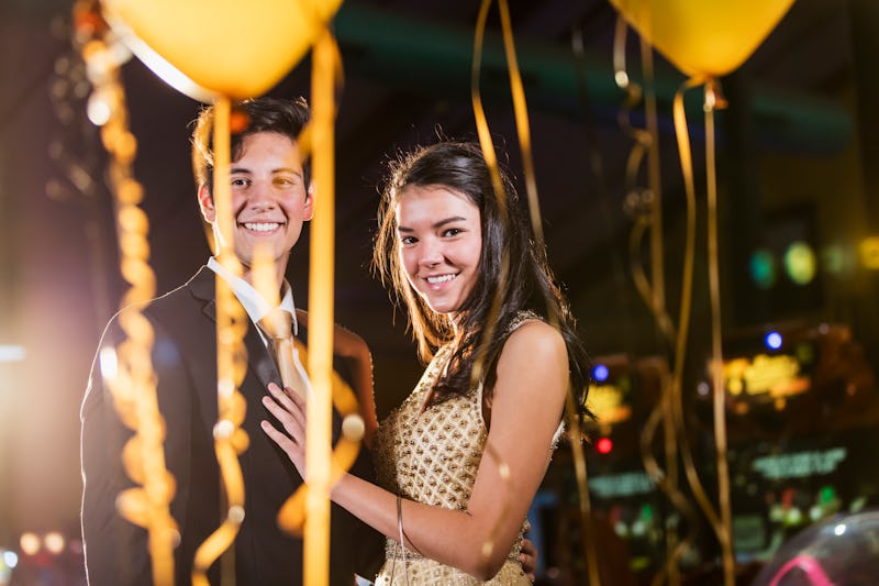 A multi-ethnic teenage couple having fun at the prom. They are both 17 years old. They are indoors a...