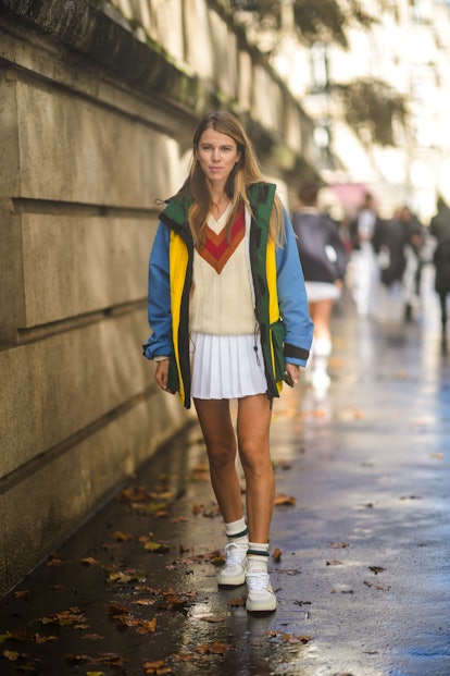 This street style look includes a V-neck sweater, pleated white mini skirt and a blue, yellow and gr...