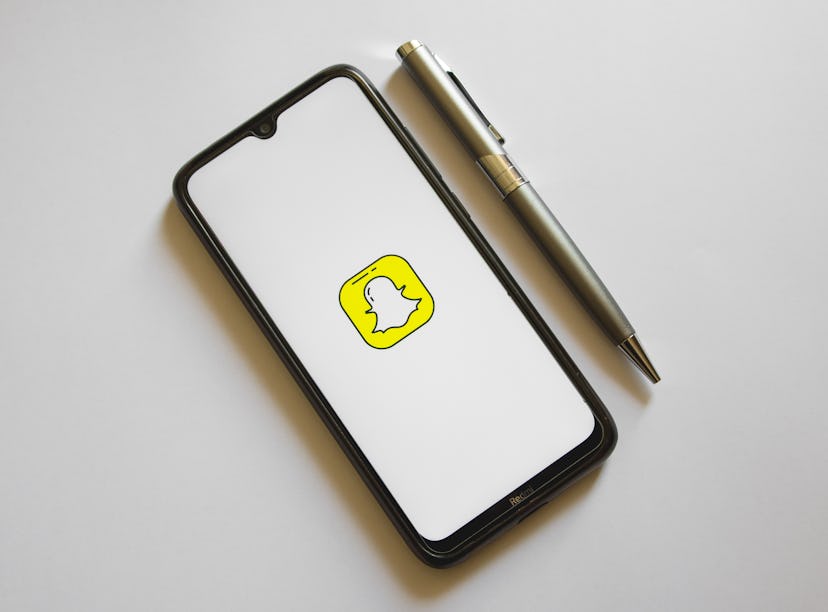 In this photo illustration a Snapchat logo is display on a smartphone screen and a pencil in Athens,...
