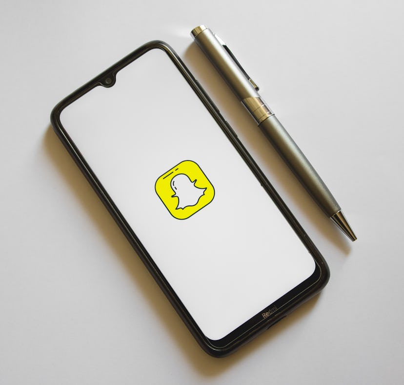 In this photo illustration a Snapchat logo is display on a smartphone screen and a pencil in Athens,...