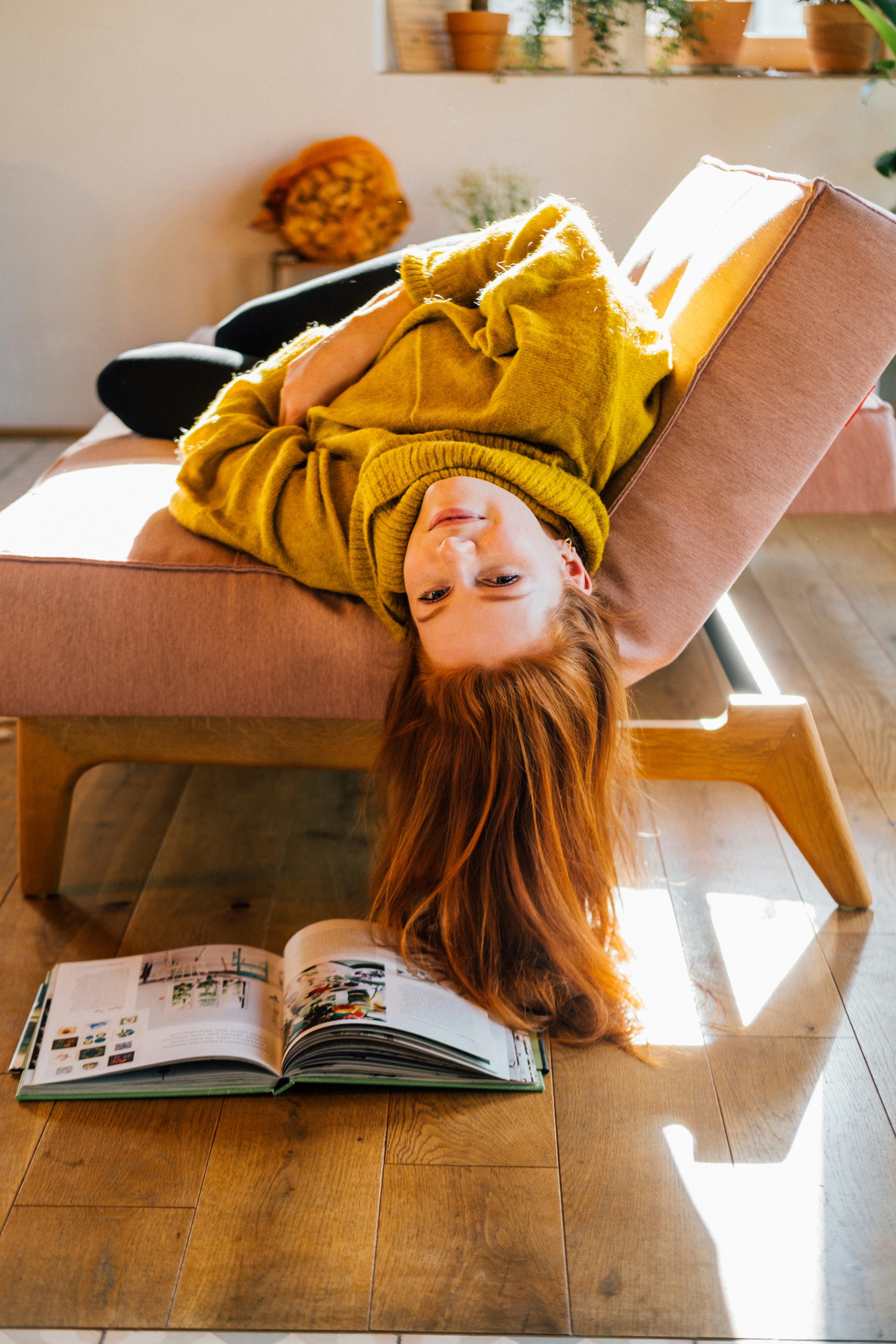 young woman hangs upside down from couch as she reflects on mercury retrograde winter 2022 ending