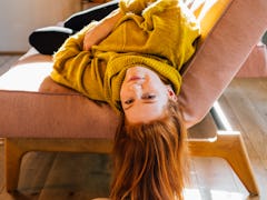 young woman hangs upside down from couch as she reflects on mercury retrograde winter 2022 ending