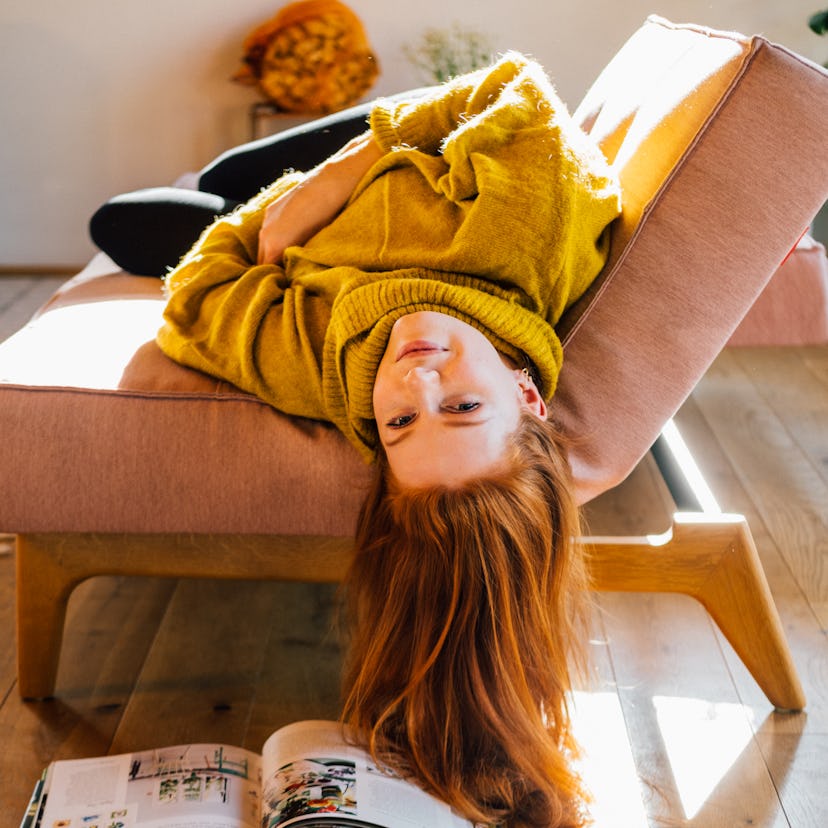 young woman hangs upside down from couch as she reflects on mercury retrograde winter 2022 ending