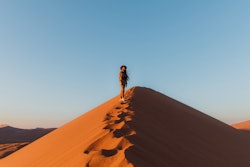 A woman walks up a sand dune at dawn. Here's the spiritual meaning of the February 20222 new moon, a...
