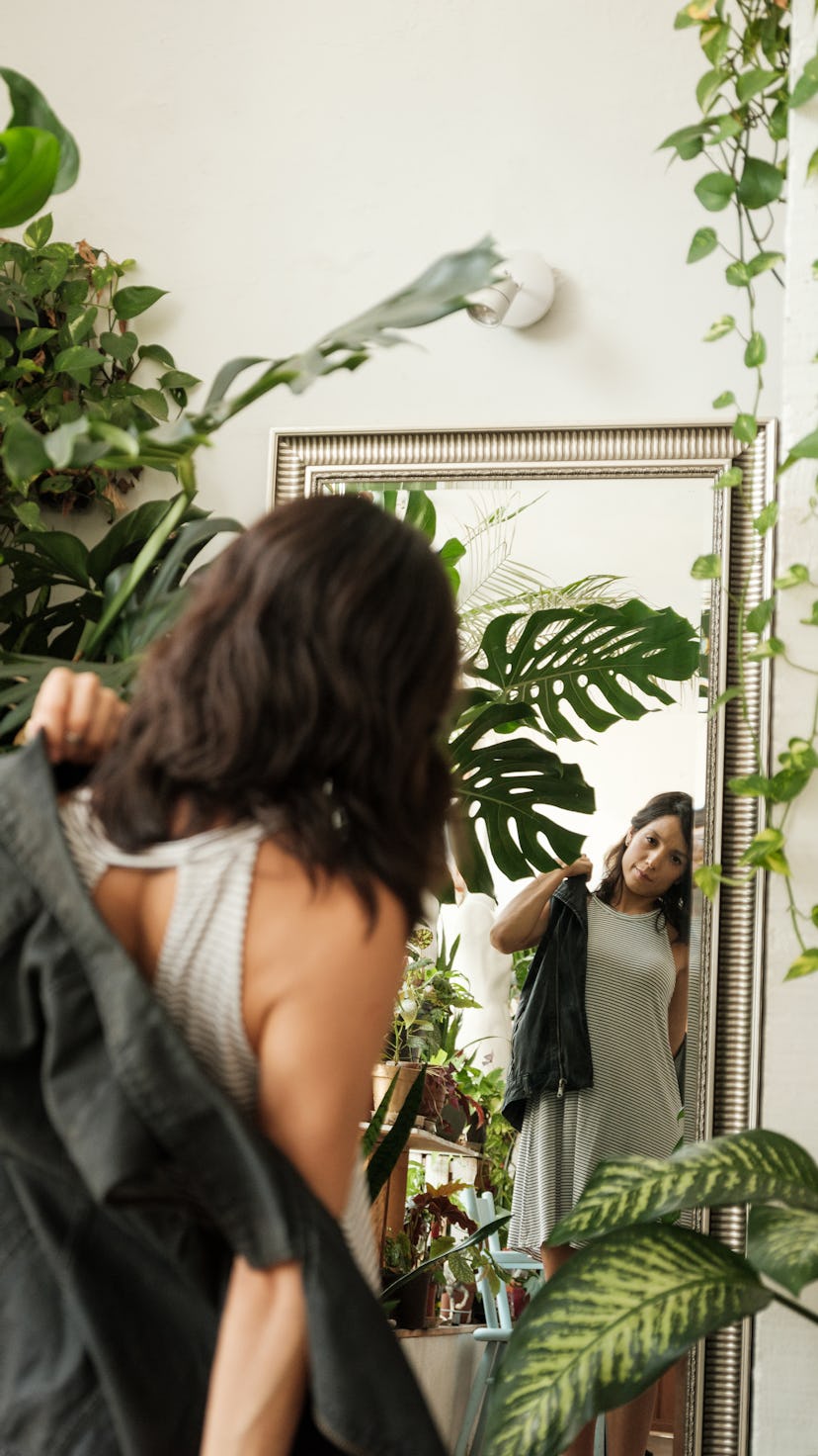 A woman standing in front of the mirror in a clothing shop trying on clothes. During the February 20...