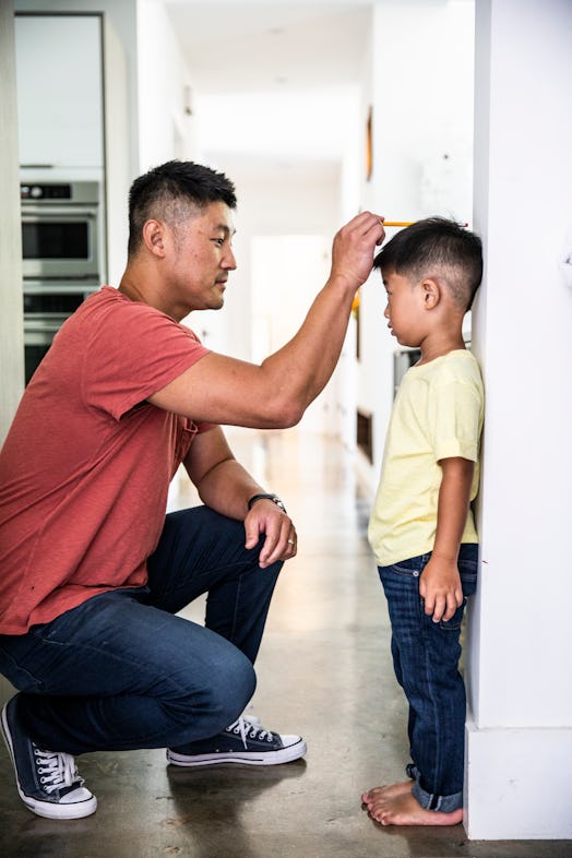 Father measuring son's height on wall