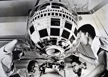 Photograph taken during the production of the Thor-Delta rocket. Technicians mate the Telstar commun...