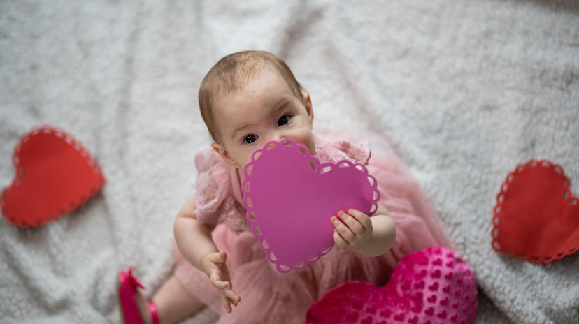 A cute baby girl dressed in pink is enjoying a Valentines day photo shoot