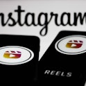 Instagram Reels logos displayed on a phone screens and Instagram logo displayed on a screen in the b...