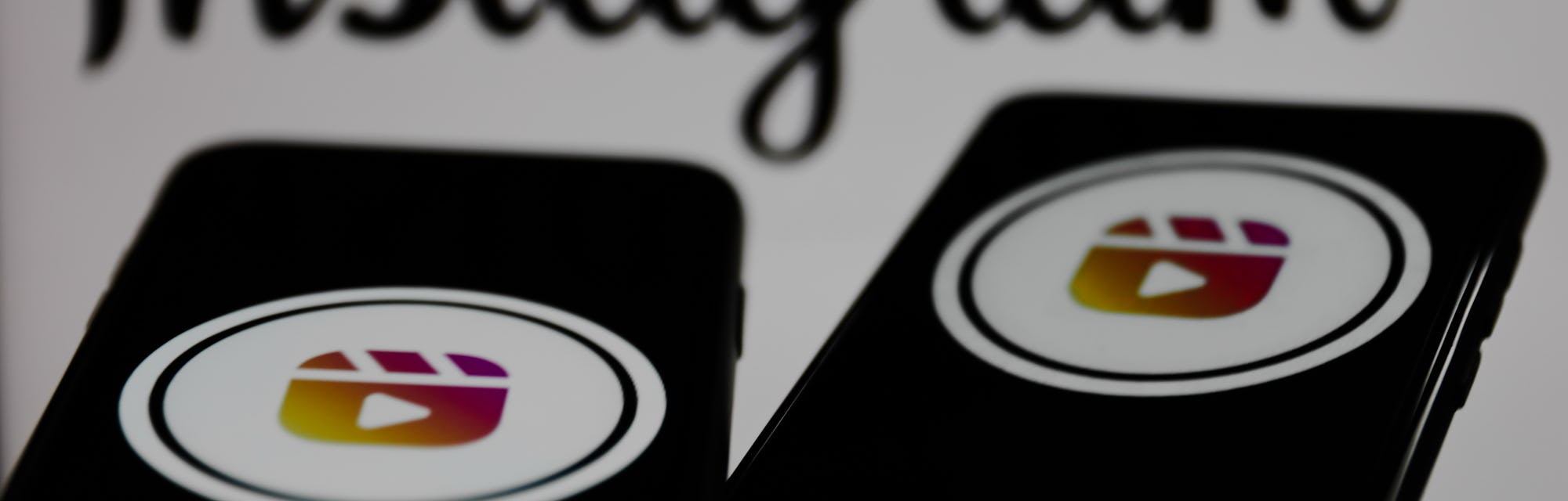 Instagram Reels logos displayed on a phone screens and Instagram logo displayed on a screen in the b...