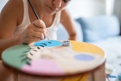 A woman paints a colorful table. The February 2022 new moon will affect these zodiac signs the most.