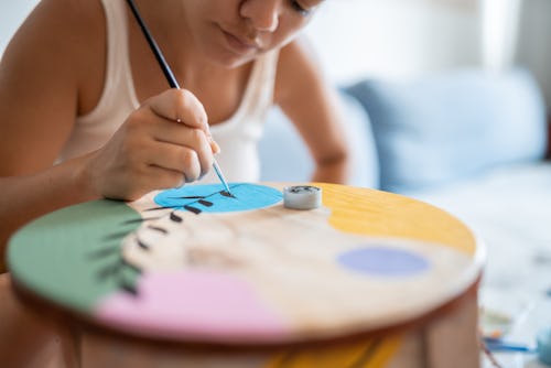 A woman paints a colorful table. The February 2022 new moon will affect these zodiac signs the most.