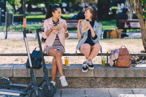 Two friends spending the day in the city park riding motor scooters