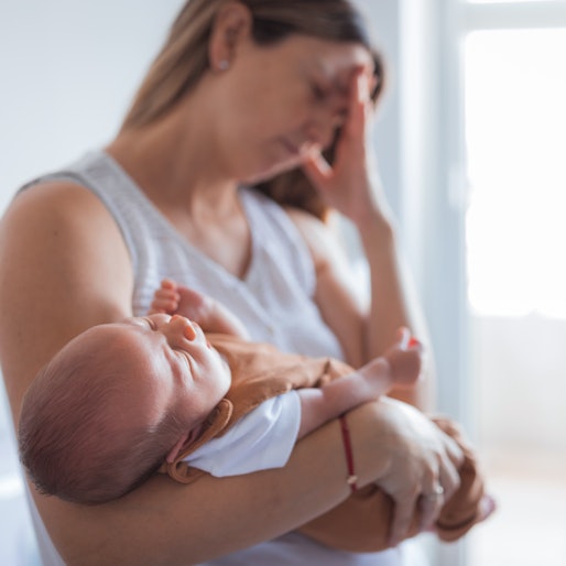 Woman putting baby to sleep while having a severe head pain