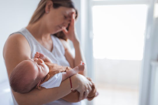 Woman putting baby to sleep while having a severe head pain