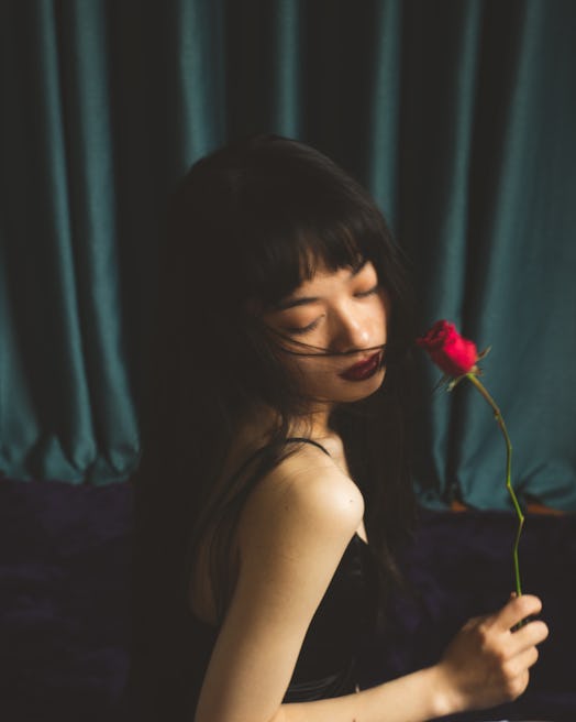 Young woman holding a red rose on Valentine's Day 2022, ready for her horoscope.
