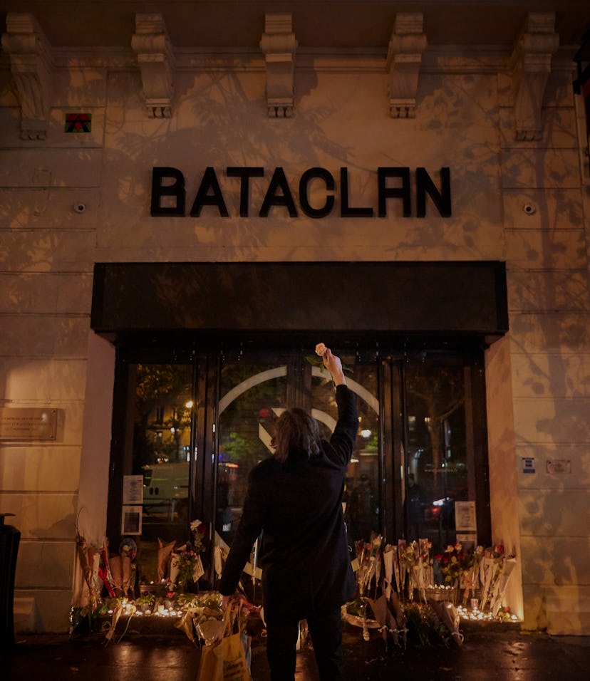 PARIS, FRANCE - NOVEMBER 13: A Parisian holds a flower towards the Bataclan concert hall on the sixt...