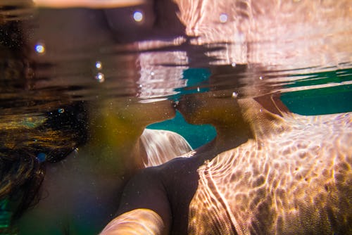 A couple kisses in a selfie taken underwater. Here are valentine's day photo dump instagram caption ...