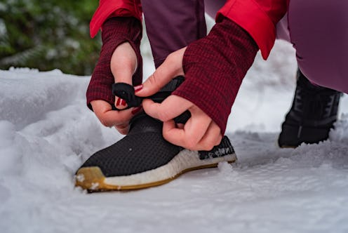Unrecognizable woman tying shoelaces on her sneakers in the cold winter day