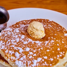 Image of Classic stack of pancakes sprinkled with powdered sugar and topped with butter dollop and s...