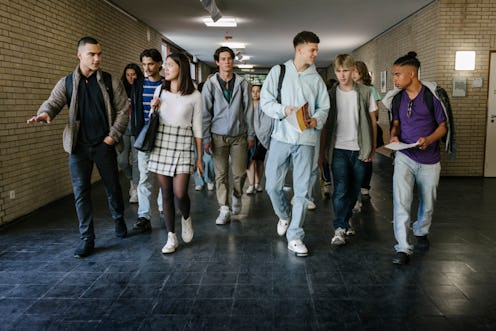 A group of high school students walking down the corridor together on their way to class.