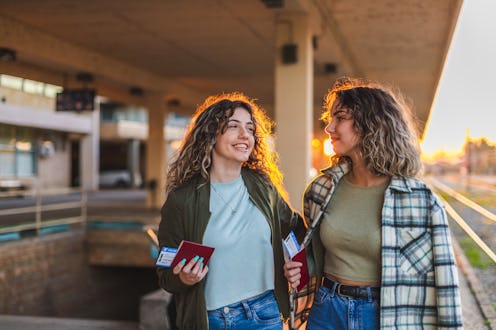 Two beautiful female friends laughing and talking at a train station.
