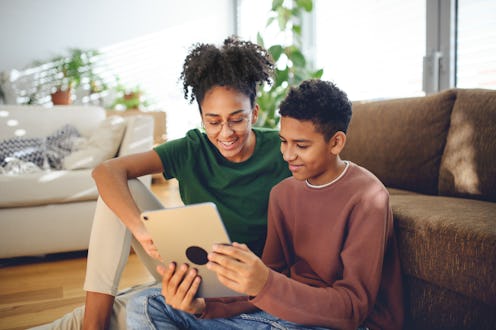Happy adolescent siblings with with tablet at home.
