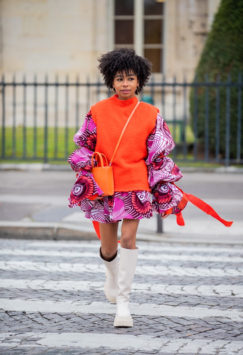 PARIS, FRANCE - JANUARY 25: A guest is seen wearing orange slipover, dress, boots, bag outside Chane...