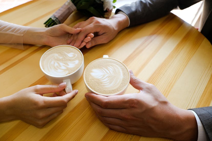 A man and a woman holding hands in a cafe, drinking coffee, in an article about dirty valentine's da...
