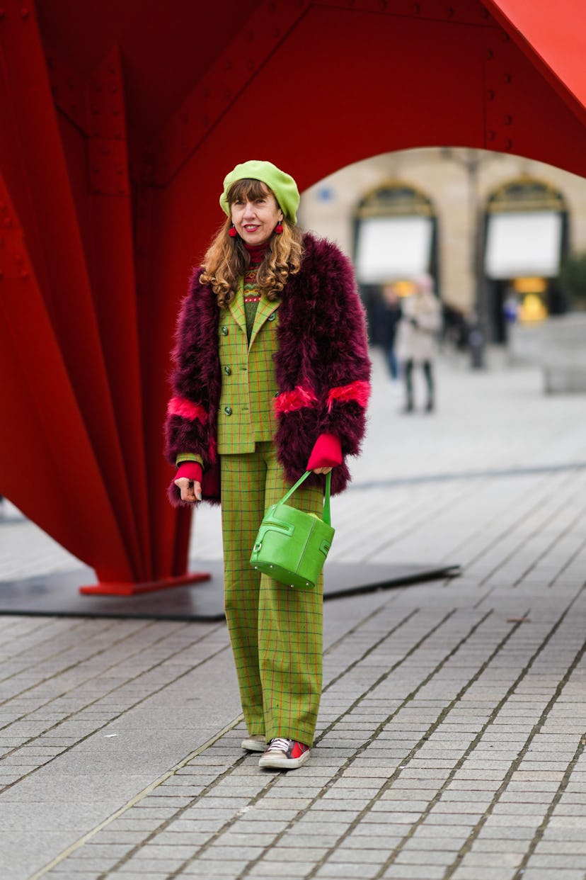 PARIS, FRANCE - JANUARY 26: A guest wears a green felt / wool beret, red pendant earrings, a dark gr...
