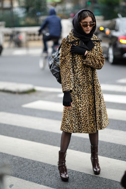 PARIS, FRANCE - JANUARY 26: A guest wears a black scarf, sunglasses, black mittens, a yellow / brown...