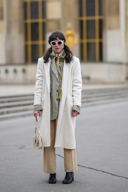 PARIS, FRANCE - JANUARY 25: A guest wears white sunglasses, gold earrings, a khaki / brown / white p...