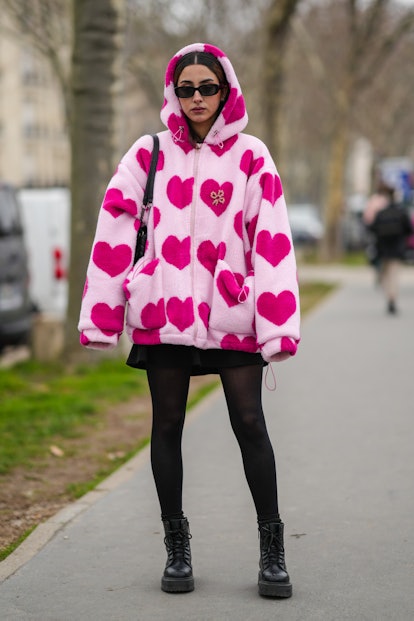 PARIS, FRANCE - JANUARY 25: A guest wears black sunglasses, a pale pink and purple heart print patte...