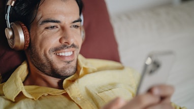 Smiling man at home enjoying good music from smartphone. Checking social media and text messaging