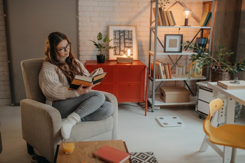 Beautiful young woman relaxing with book  at home