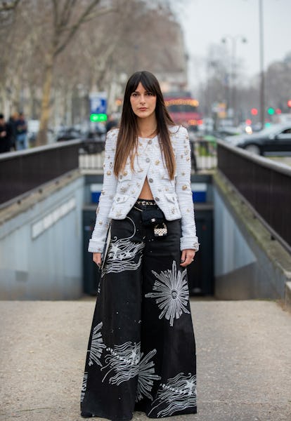 PARIS, FRANCE - JANUARY 25: A guest is seen wearing black wide leg pants with print, white jacket, m...