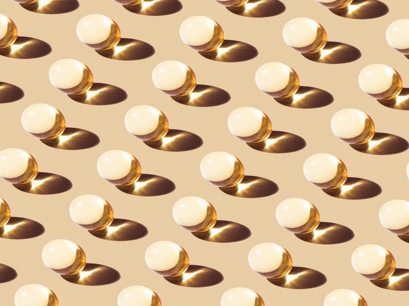 Transparent Yellow Fat-soluble Vitamin Soft Capsule Repetition Pattern on Beige Background Full Fram...