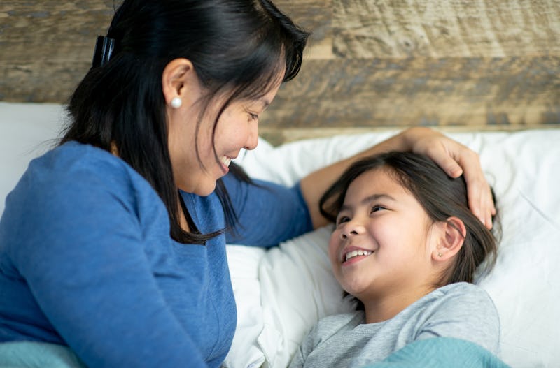 A Filipino mother lays beside her young daughter as she tucks her into bed for the night. They are ...