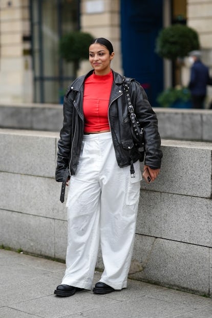 PARIS, FRANCE - JANUARY 26: A model wears a red turtleneck pullover, a black shiny leather jacket, a...