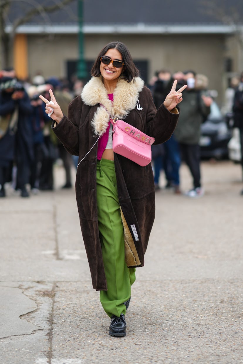 PARIS, FRANCE - JANUARY 25: A model wears sunglasses, a neon pink pullover, a brown suede with pale ...