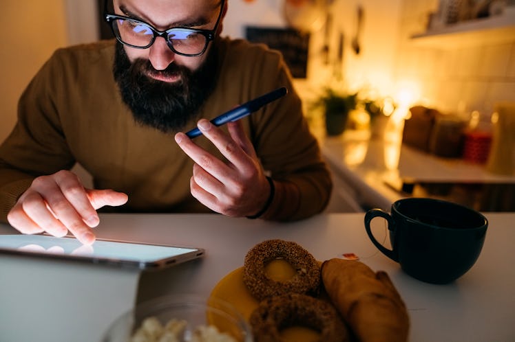 Man uses the tablet while working late at night while dinner is standing next to him