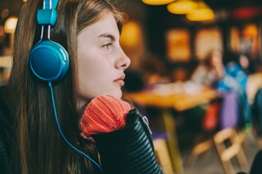 Young girl with headphones at cafeteria listening podcast