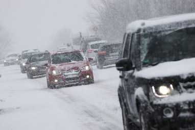 09 February 2021, Schleswig-Holstein, Neustadt: Heavy snowfall hinders traffic on a country road nea...