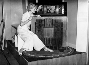 Woman watching a Marconi mirror lid television, Radiolympia, London, 1936. Photograph showing a woma...